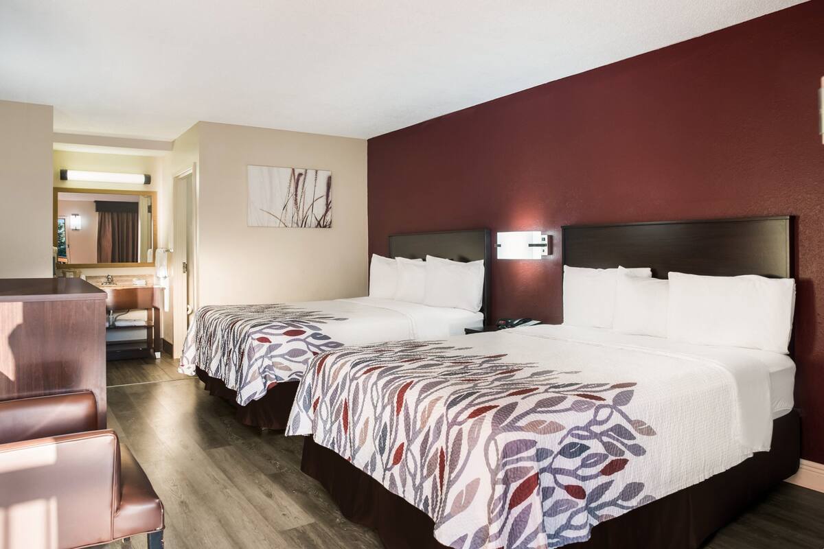 A hotel room with two beds, a desk, and a chair.