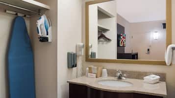 A bathroom with a sink, mirror, hanging clothes rack, and a blue ironing board.