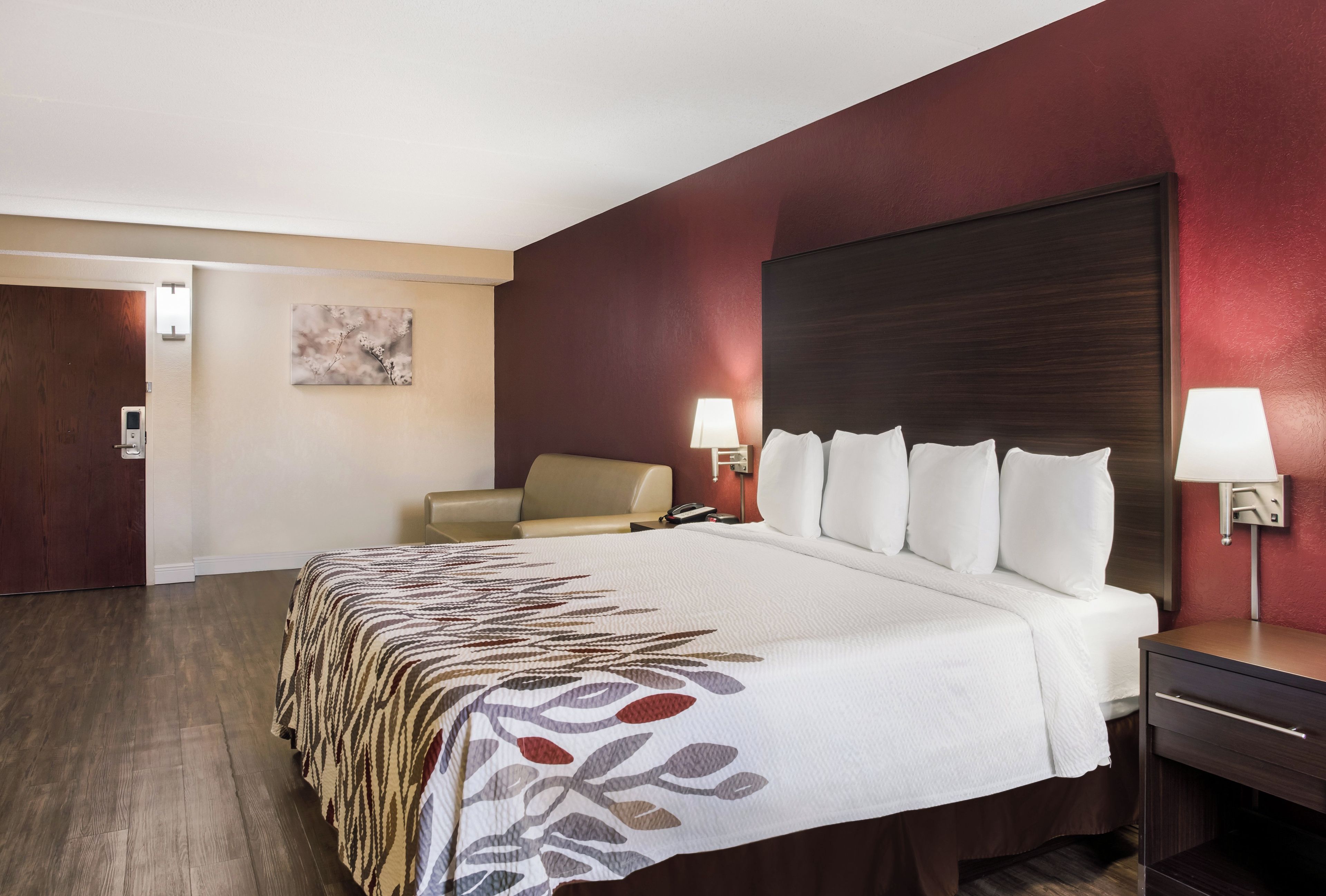 Una habitación de hotel con una cama, una silla, un escritorio y una mesita de noche.