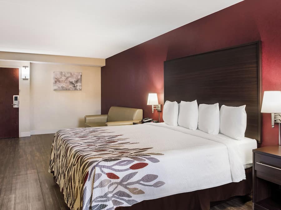 A hotel room with a bed, a chair, a desk, and a nightstand.