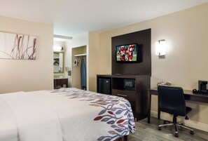 A hotel room with a bed, a desk, a television, and a mirror. - Red Roof Inn Tupelo (Tupelo)