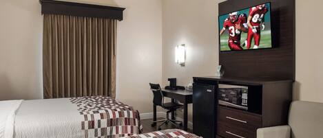Habitación de hotel con dos camas, un escritorio, una silla, un televisor y un microondas.