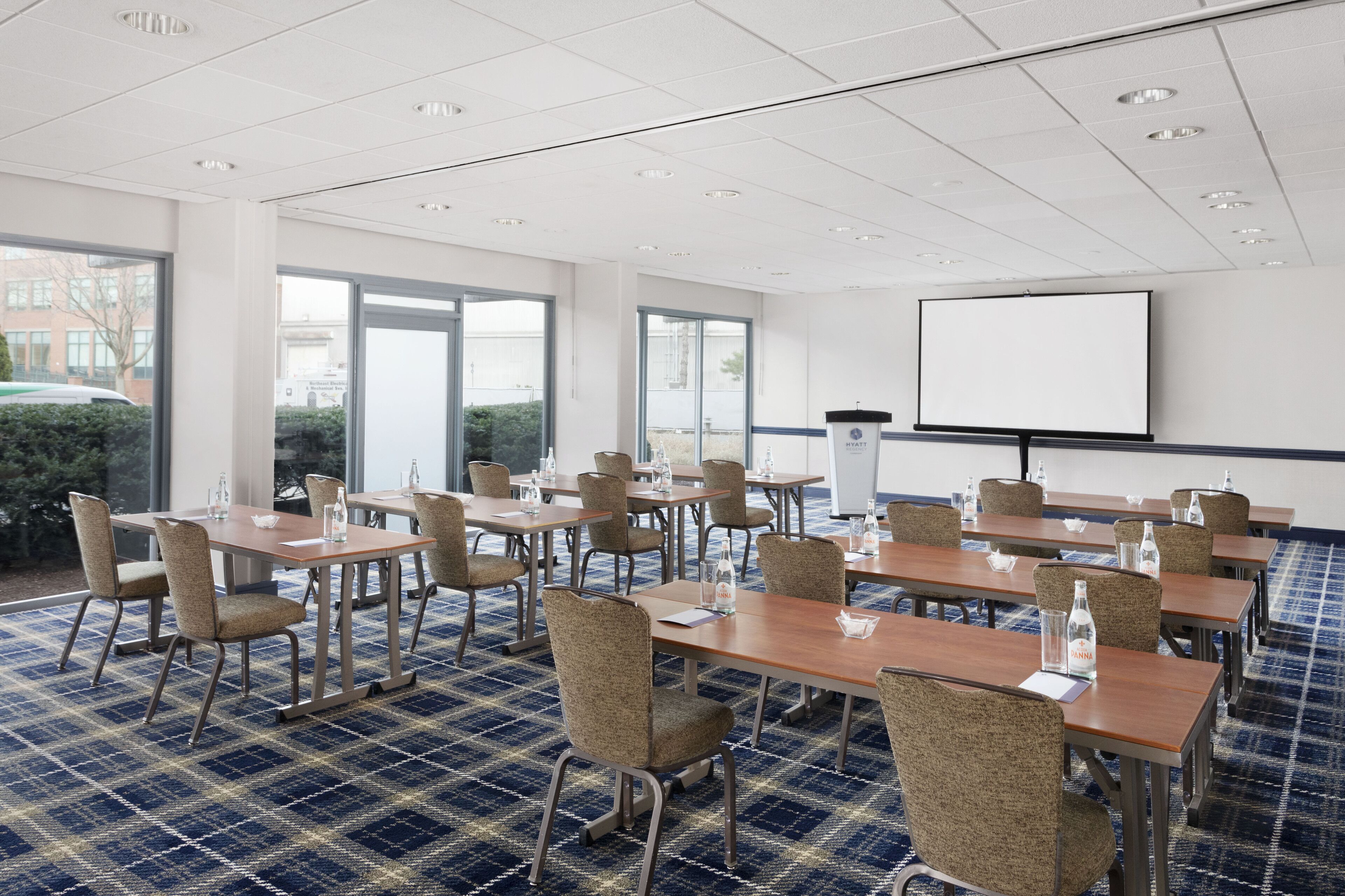 A conference room with tables and chairs, a projector screen, and a podium.