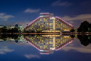 A multi-story hotel with a distinctive stepped design, featuring illuminated signage and a reflection in the water. - Hyatt Regency Boston/Cambridge (Cambridge)