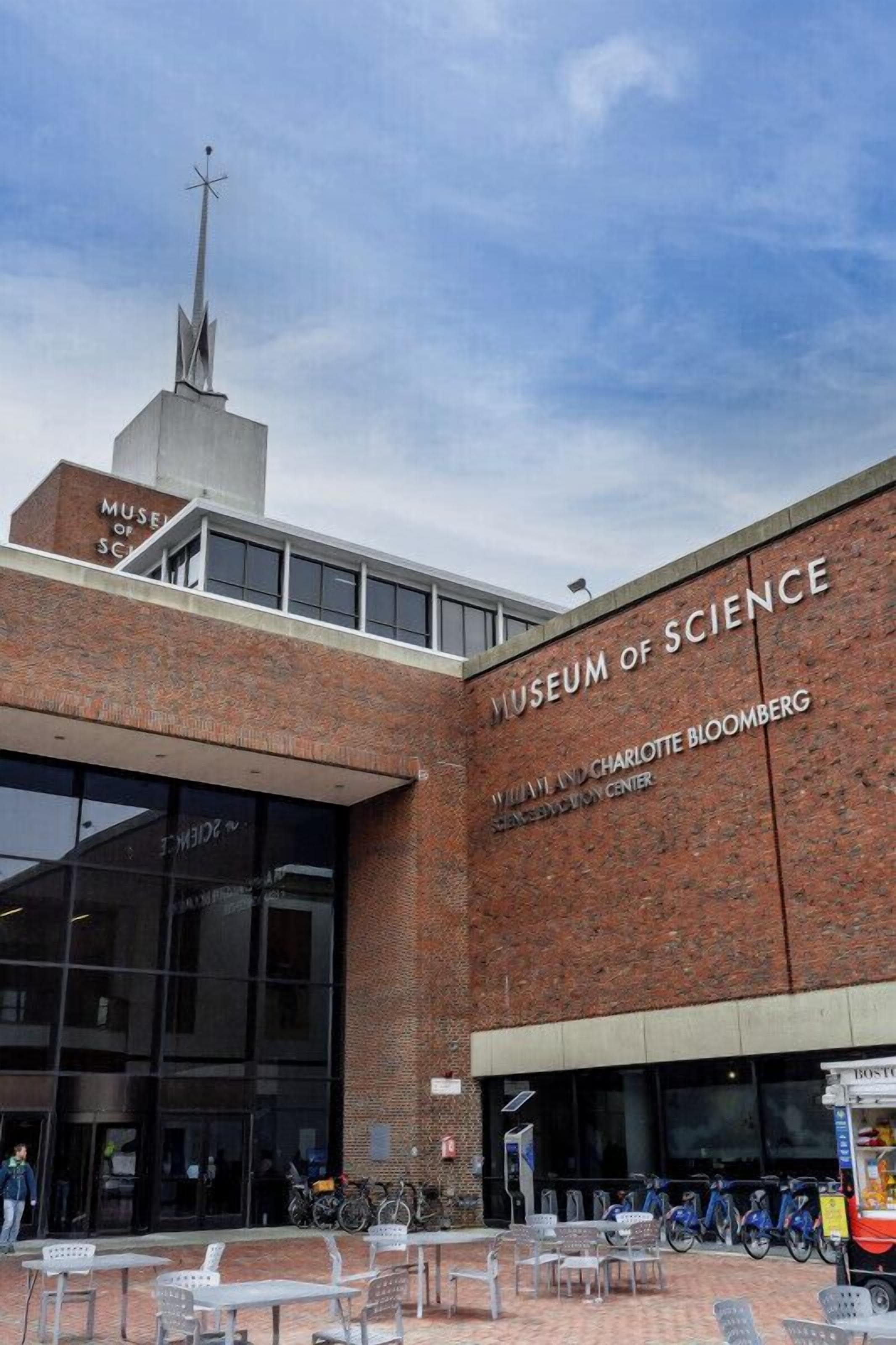 The exterior of the Museum of Science, featuring a prominent brick facade, large glass entrance, and a spire.