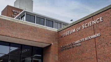 Exterior del Museo de Ciencia, con una destacada fachada de ladrillo, una amplia entrada de vidrio y una aguja.