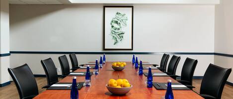 A conference room with a long table, black chairs, and a framed artwork on the wall.