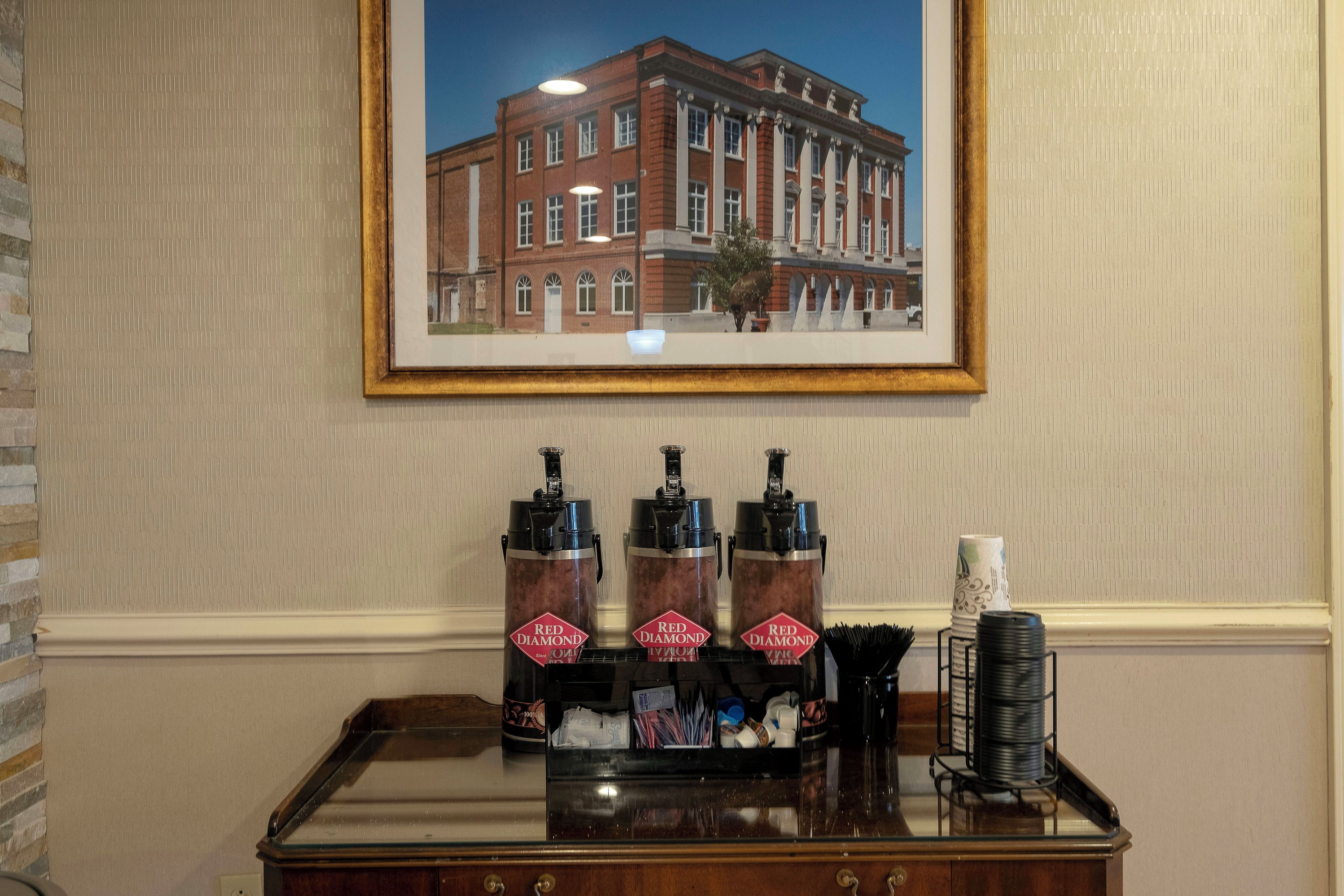 A framed picture of a building on the wall, a bar area with bottles and glasses, and a stack of coasters.