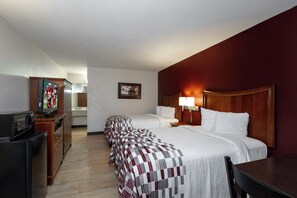 A hotel room with two beds, a desk with a television, a clock, and a framed picture on the wall. - Red Roof Inn Dothan (Dothan)
