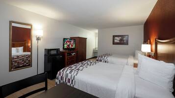 A hotel room with two beds, a television, a desk, a mirror, and a picture on the wall.