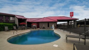A hotel with a swimming pool, outdoor seating, and a fenced patio area. - Red Roof Inn Dothan (Dothan)