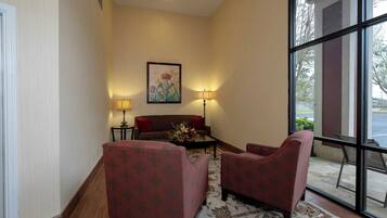 A hotel lobby with a sofa, two armchairs, a coffee table, and a painting on the wall.