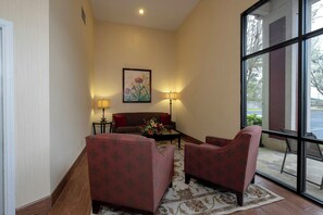 Un vestíbulo de hotel con un sofá, dos sillones, una mesa de centro y un cuadro en la pared.