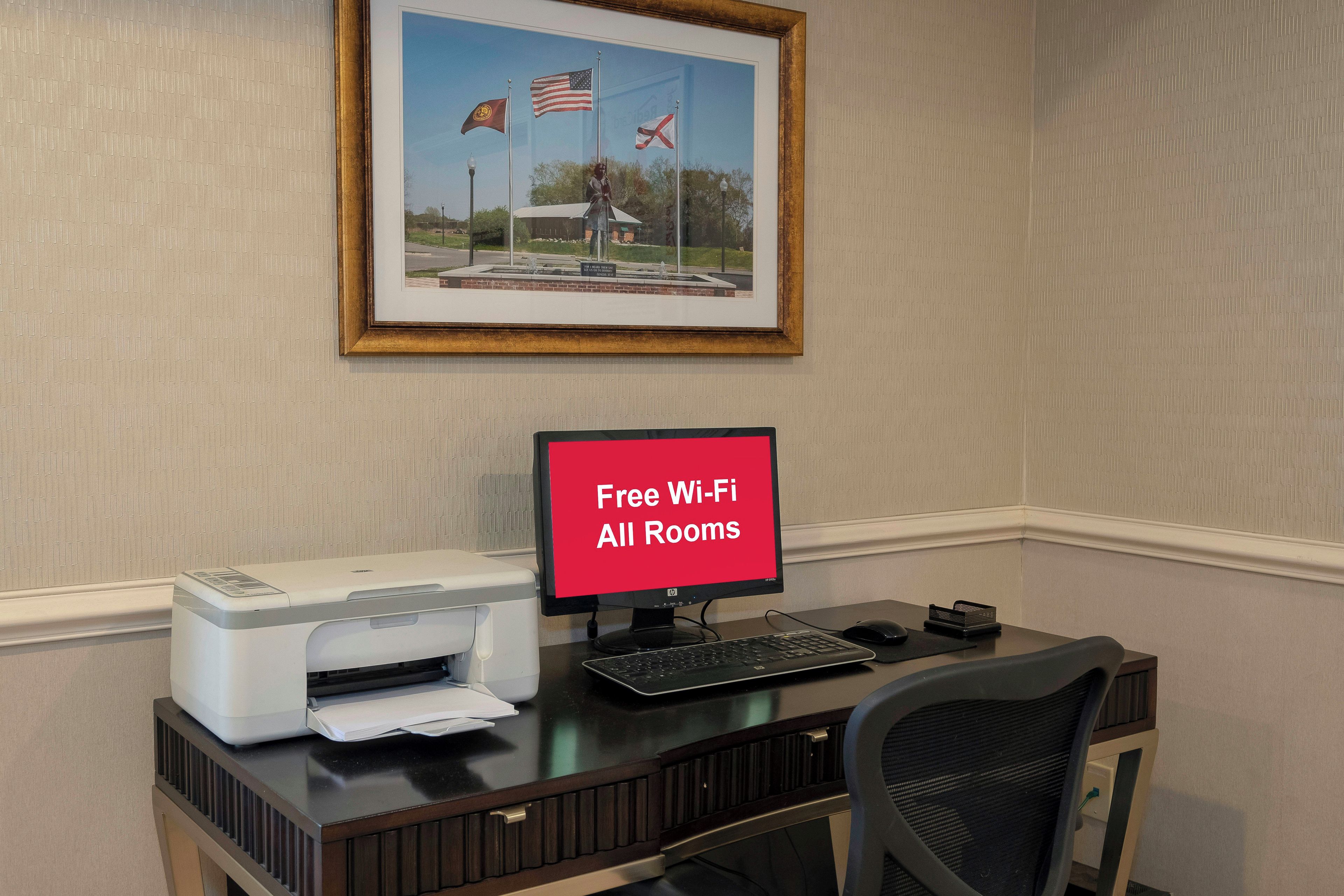 A workspace with a printer, a computer, and a sign indicating free Wi-Fi in all rooms.