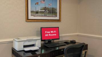 A workspace with a printer, a computer, and a sign indicating free Wi-Fi in all rooms.