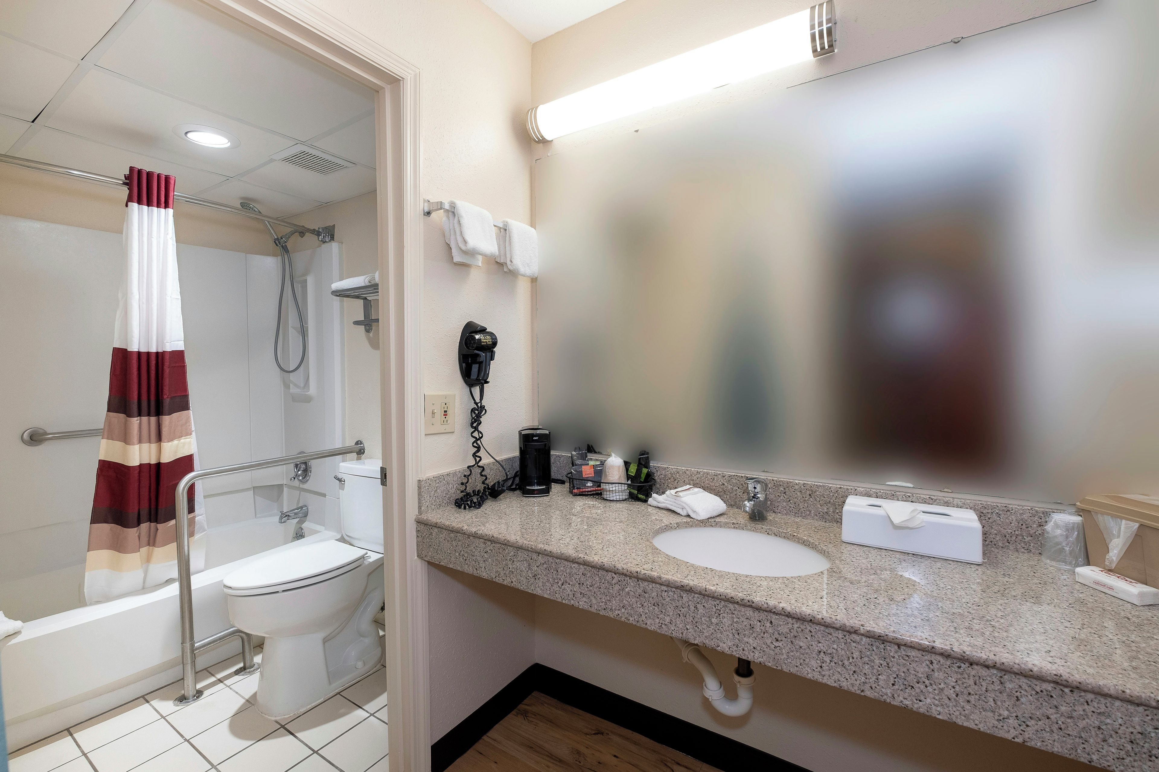 A bathroom with a shower, toilet, sink, and a mirror.