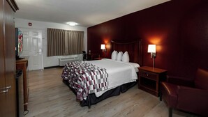 A hotel room with a bed, a desk, a chair, a television, and a window with curtains.