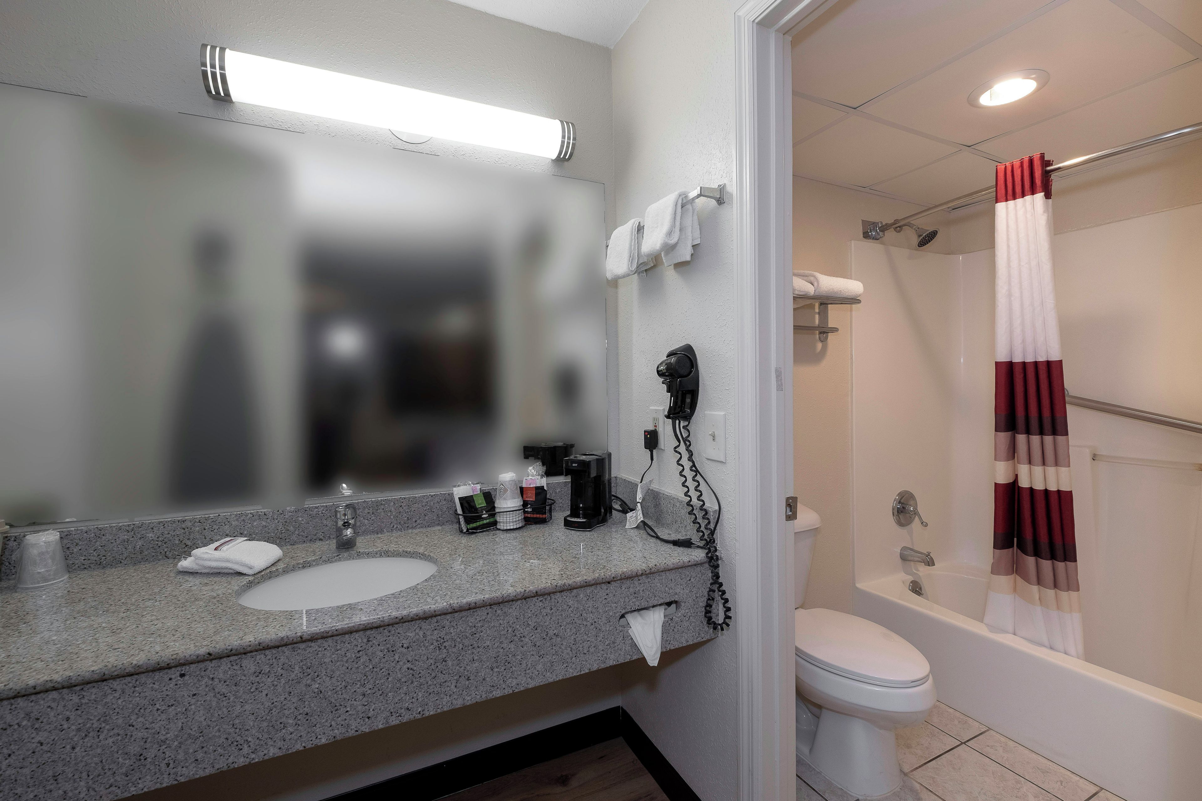 A bathroom with a sink, mirror, towel rack, and a shower area.