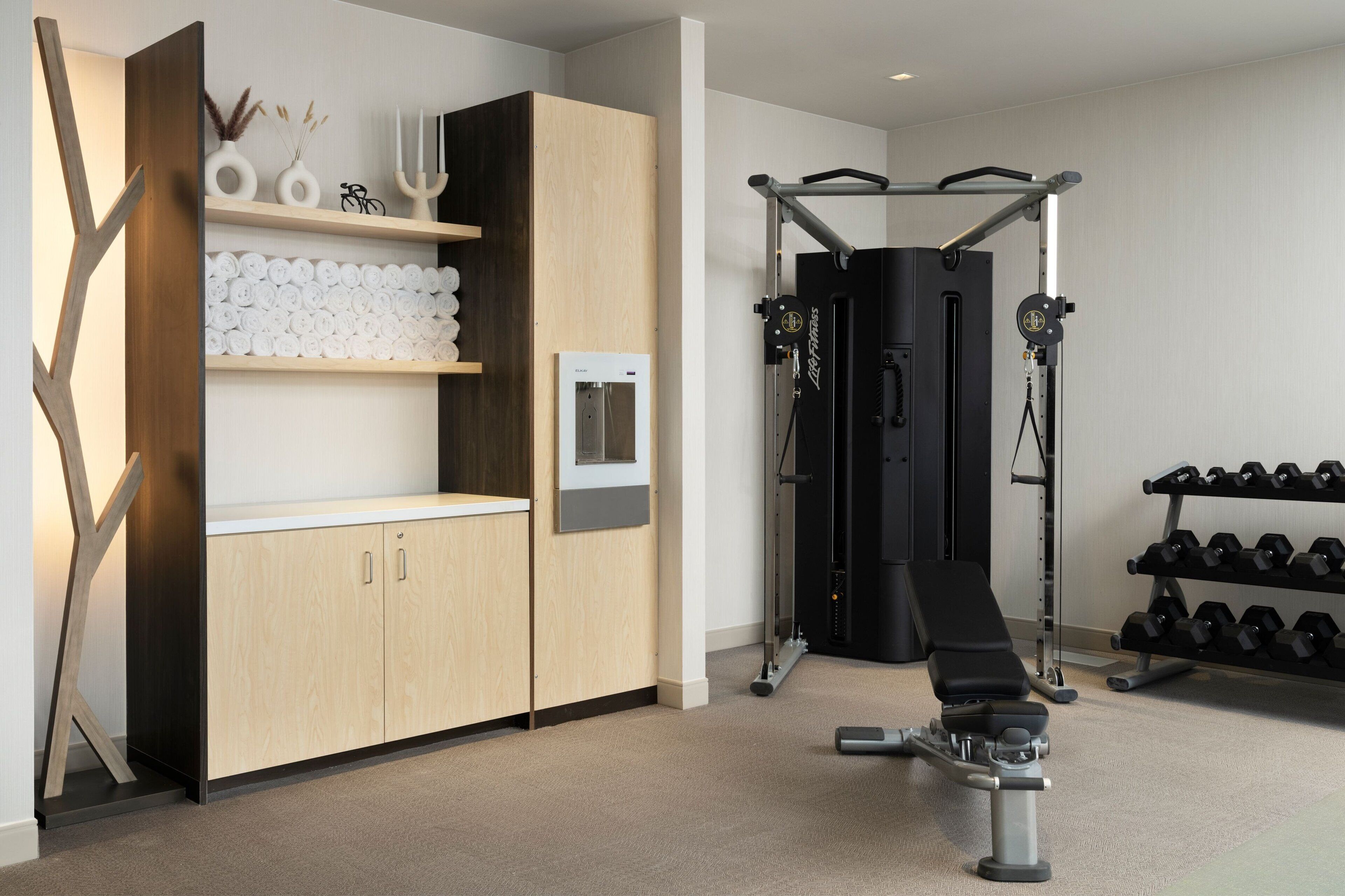 Un gimnasio moderno con barra de dominadas, banco de pesas y mancuernas.