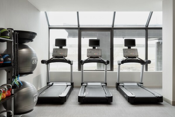 A gym with treadmills, a rowing machine, and a large exercise ball.