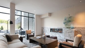 A modern living room with a stone fireplace, a large window, and a cozy seating area. - AC Hotel Frisco Colorado (Frisco)
