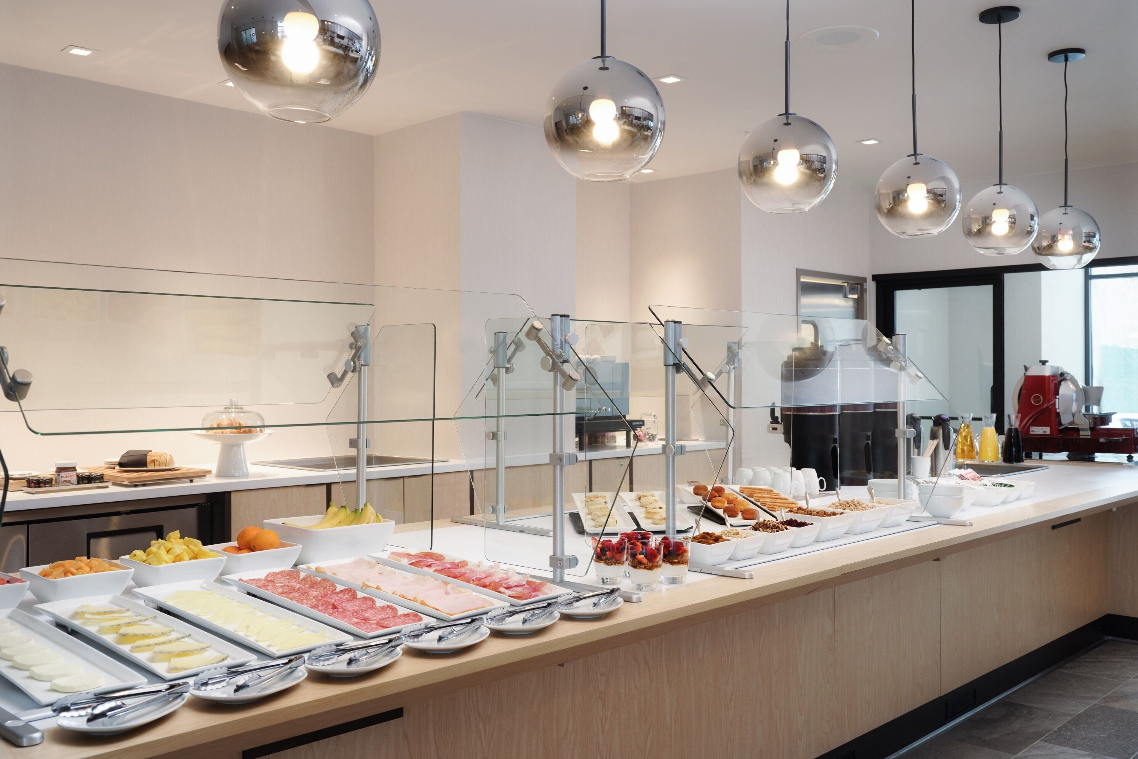 A buffet with various food items and clear glass barriers.