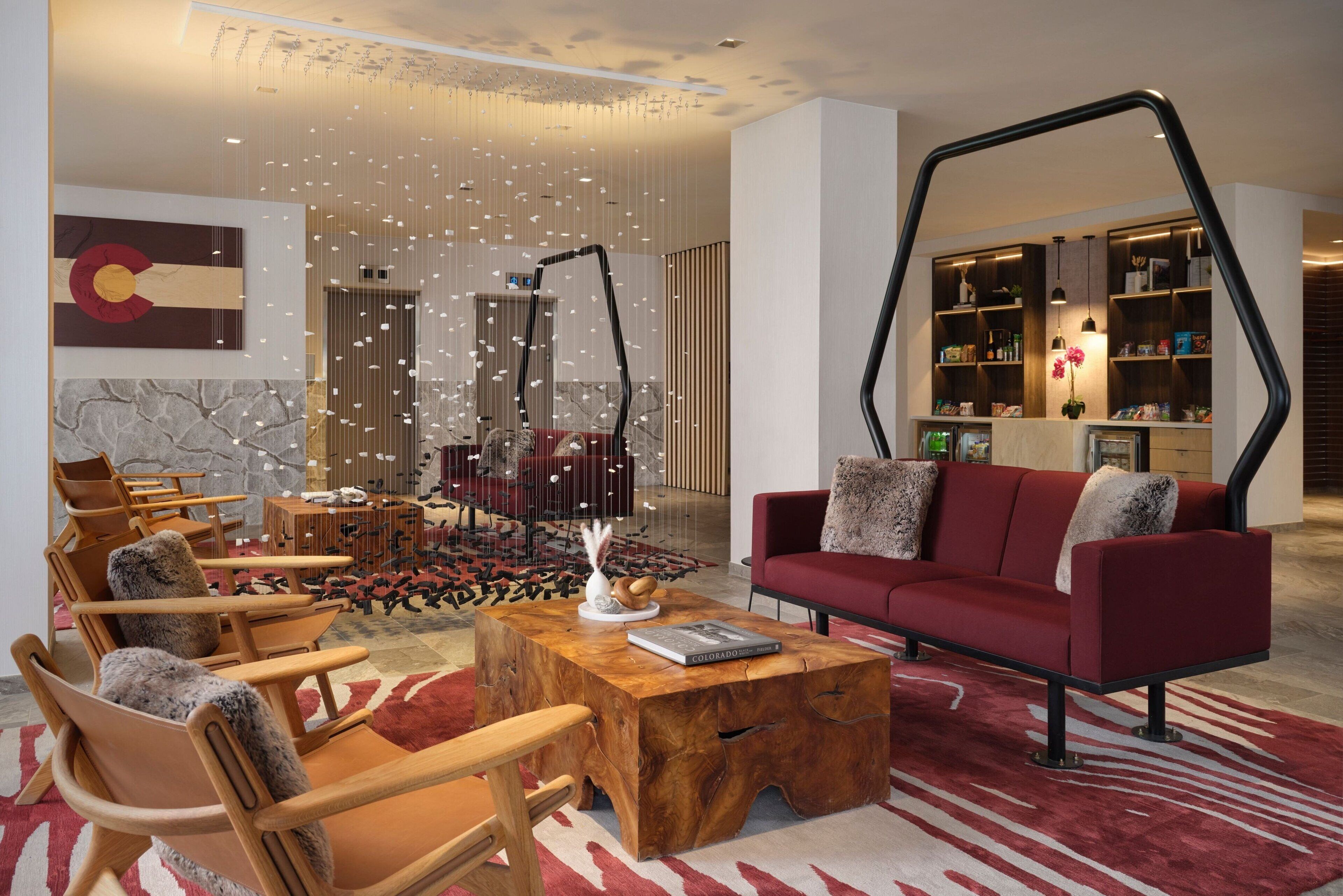 A modern living room with a red sofa, wooden chairs, a coffee table, and a bookshelf.