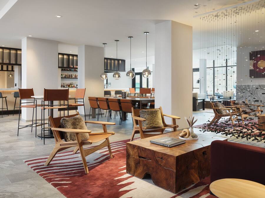Un interior moderno con una zona de bar, comedor y espacio de estar con muebles de madera y una alfombra roja.