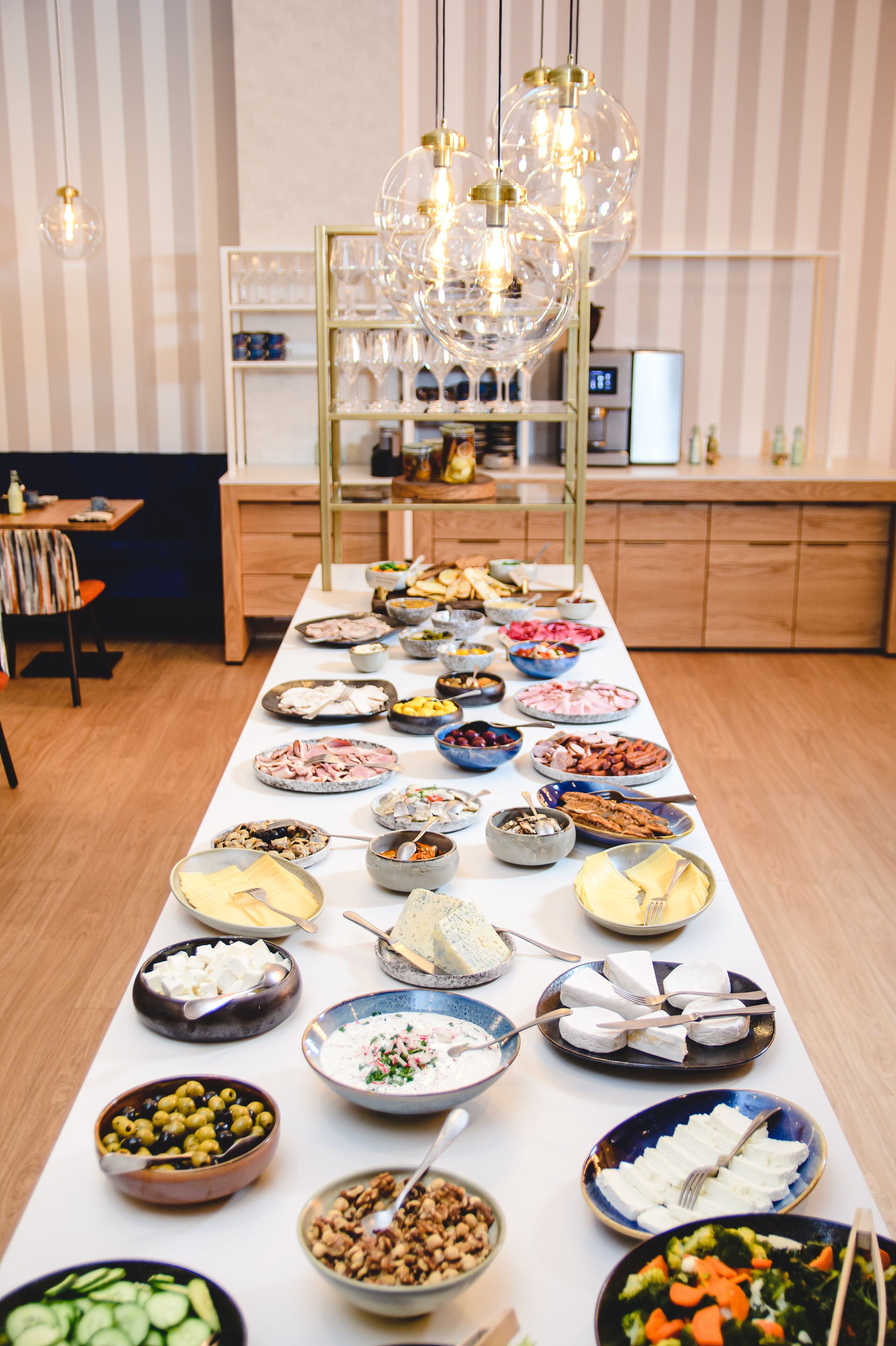 A buffet table with various food items and a wine rack in the background.
