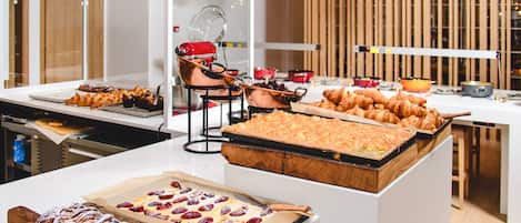 Un bufé con diversas opciones de panadería, incluyendo pasteles y postres, dispuesto sobre una barra.