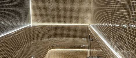 Un baño moderno con diseño curvo, paredes con azulejos y una zona de lavamanos central.
