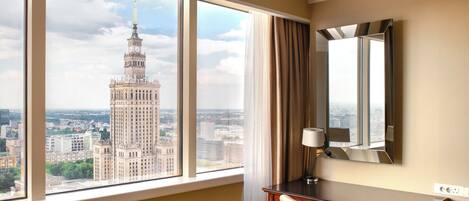 A hotel room with a large window offering a view of a historic building.