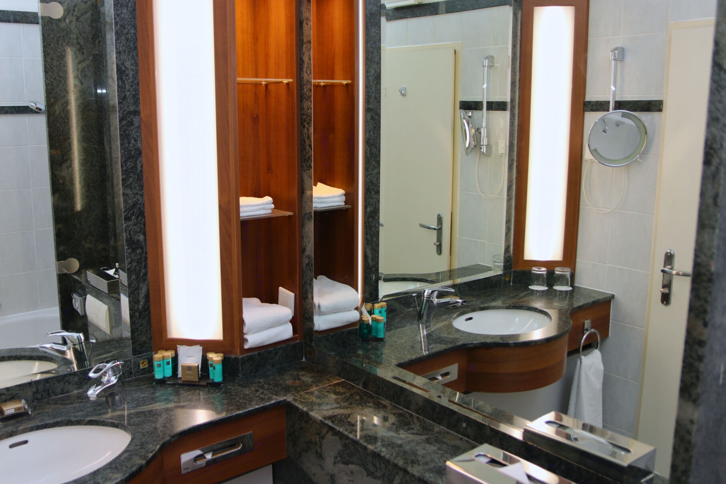 Une salle de bain moderne avec deux lavabos, un grand miroir et un espace douche.