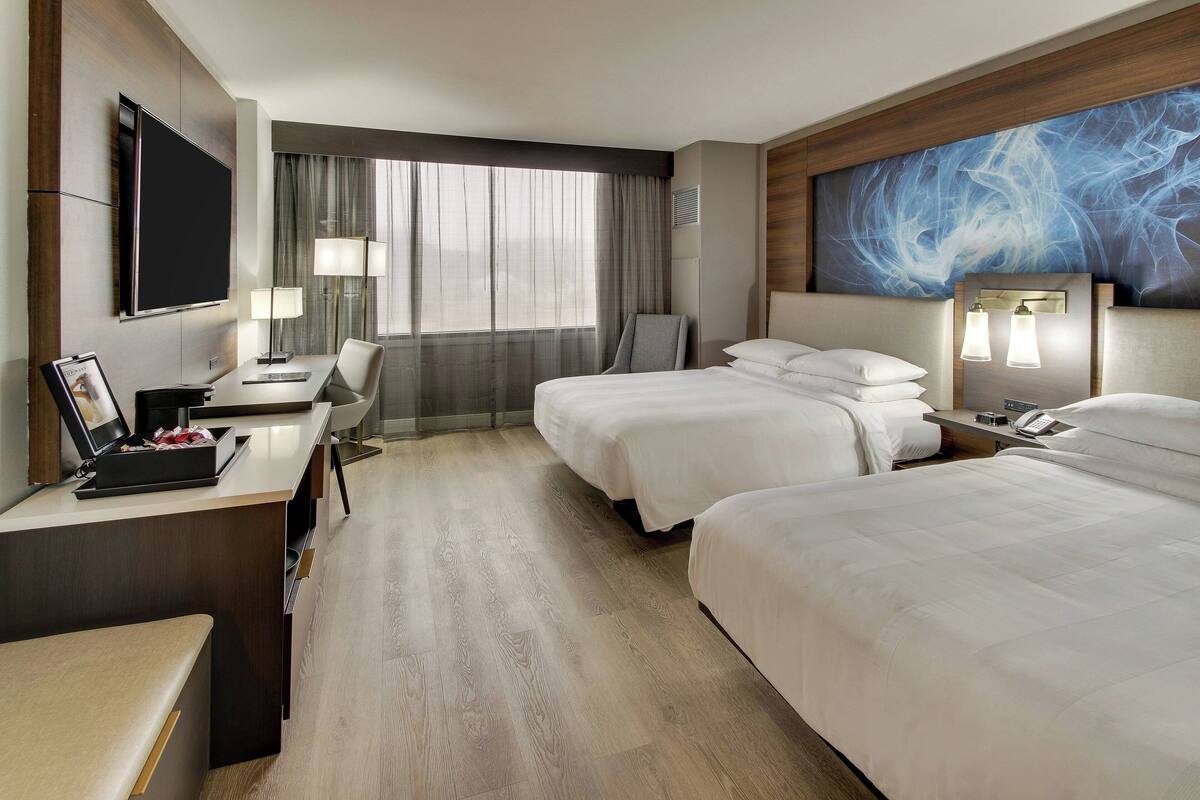A hotel room with a large bed, a desk with a computer, a chair, and a TV.