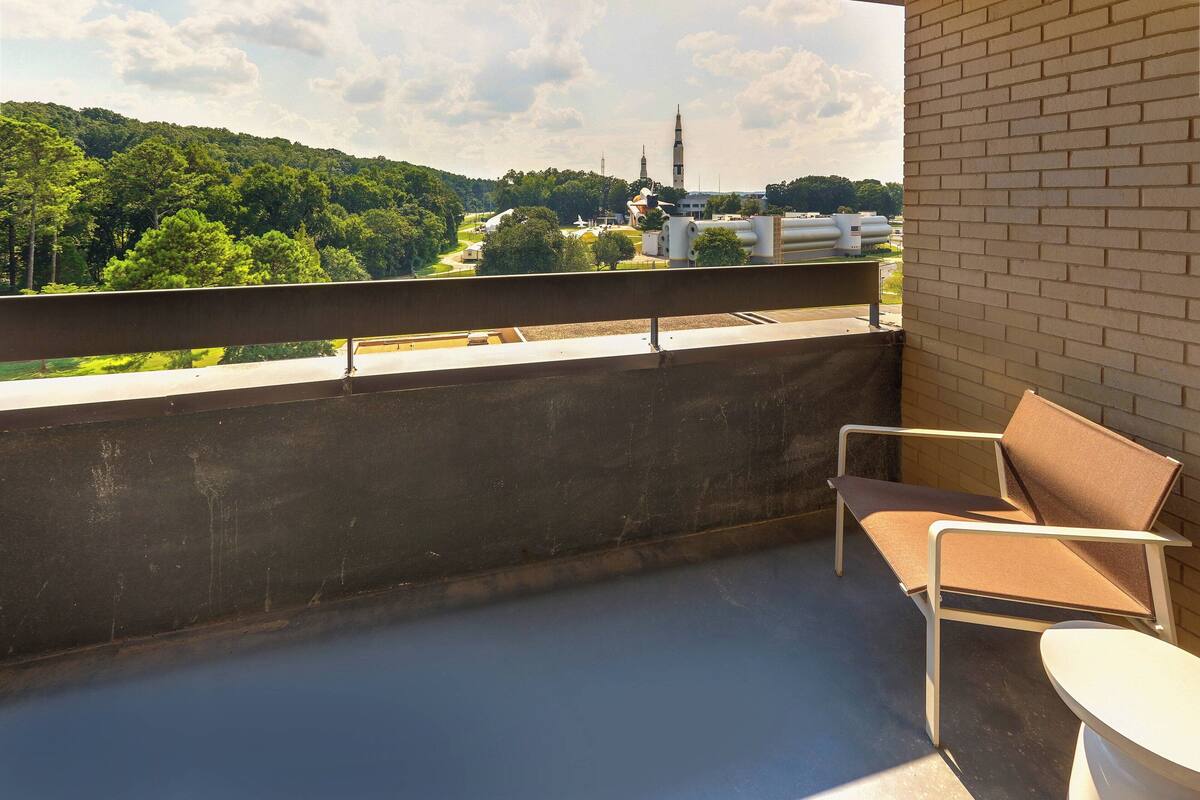 A balcony with a view of a green landscape and a building with a tower.