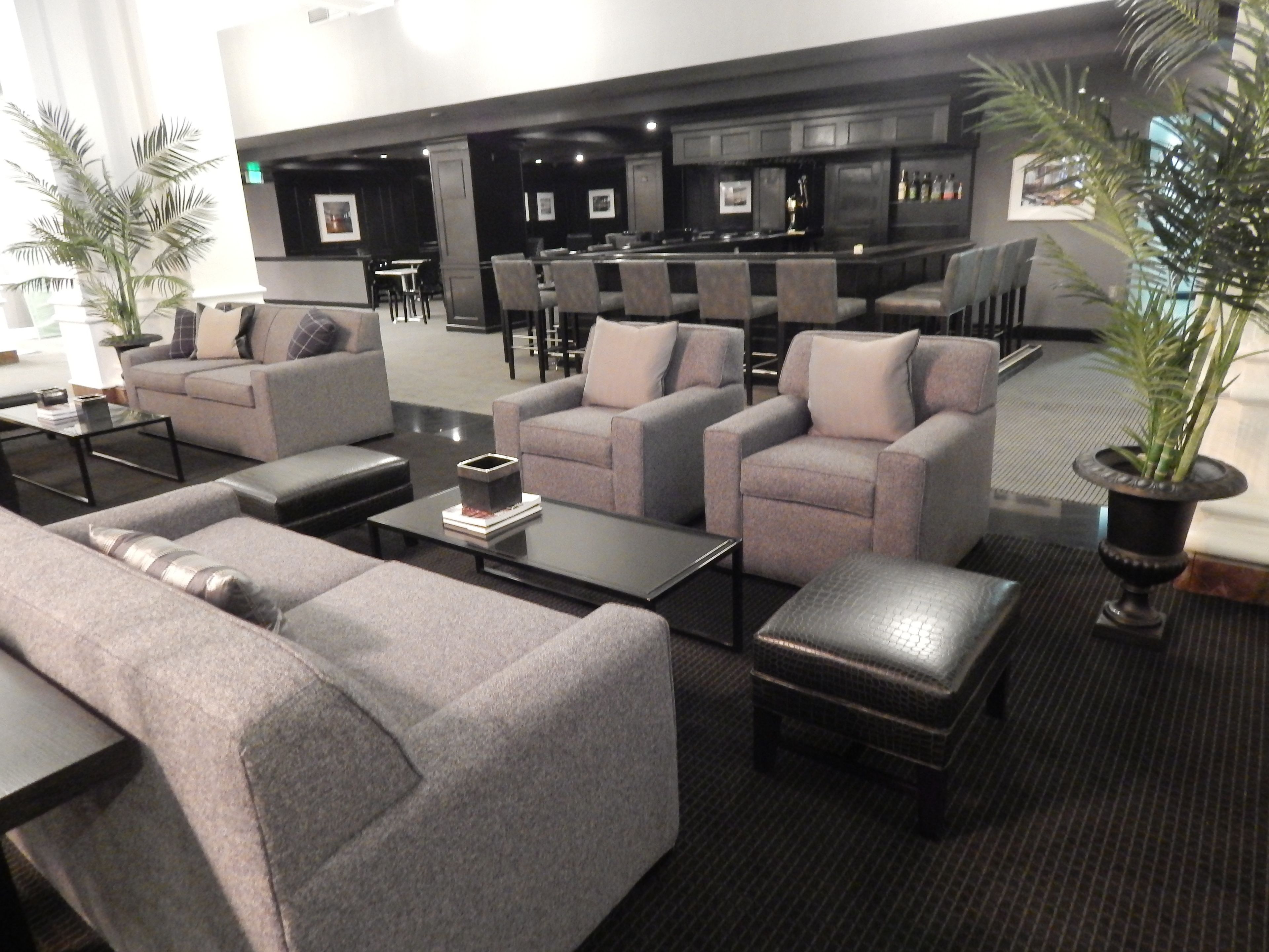 A modern lounge area with sofas, a coffee table, and a bar area in the background.