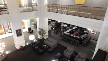 Um hall amplo com pé direito alto, diversas áreas de estar e um espaço bar/lounge.