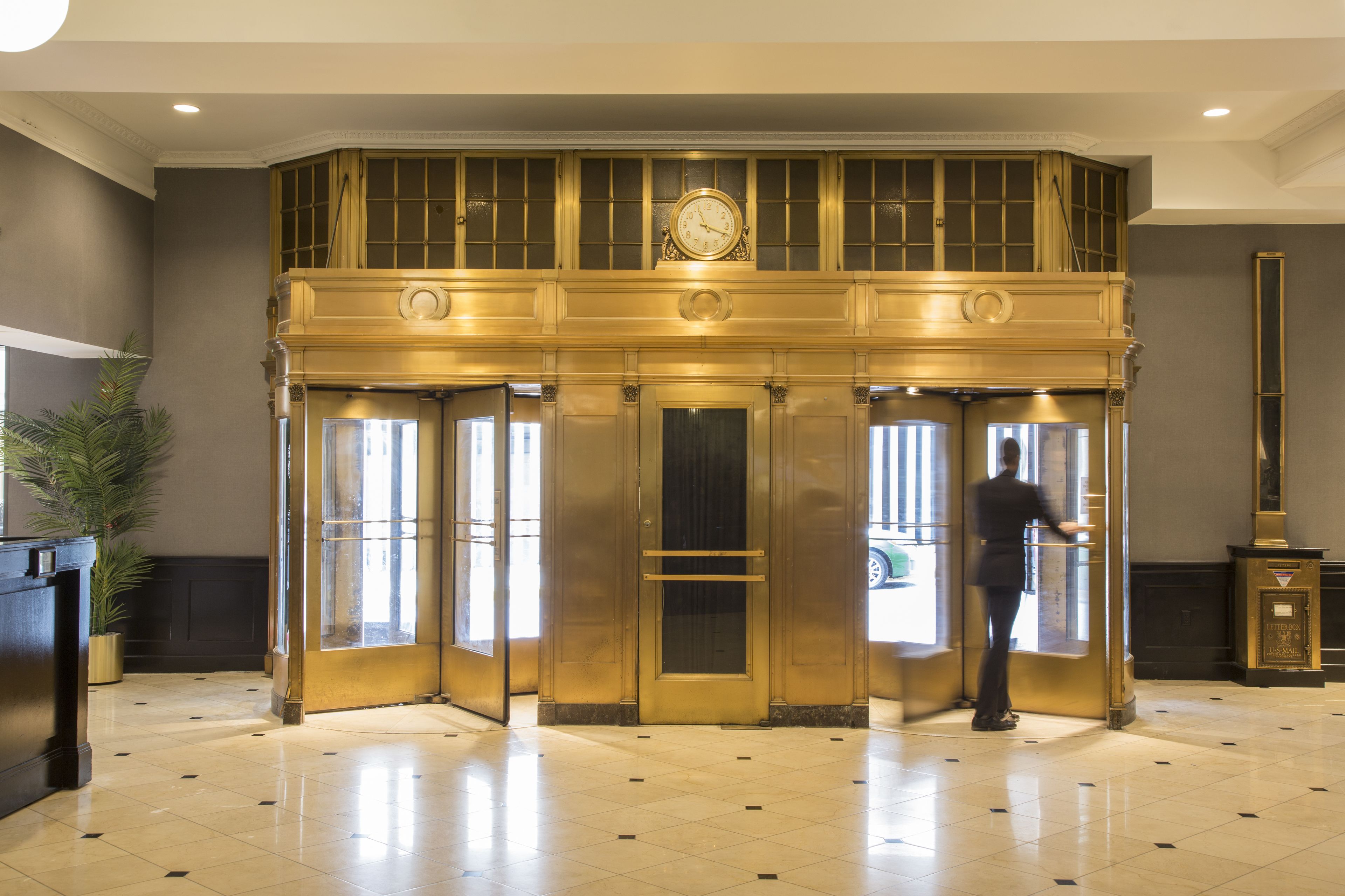 A lobby with a double door entrance, a reception desk, and a large clock above the doors.