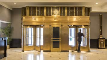 A lobby with a double door entrance, a reception desk, and a large clock above the doors.