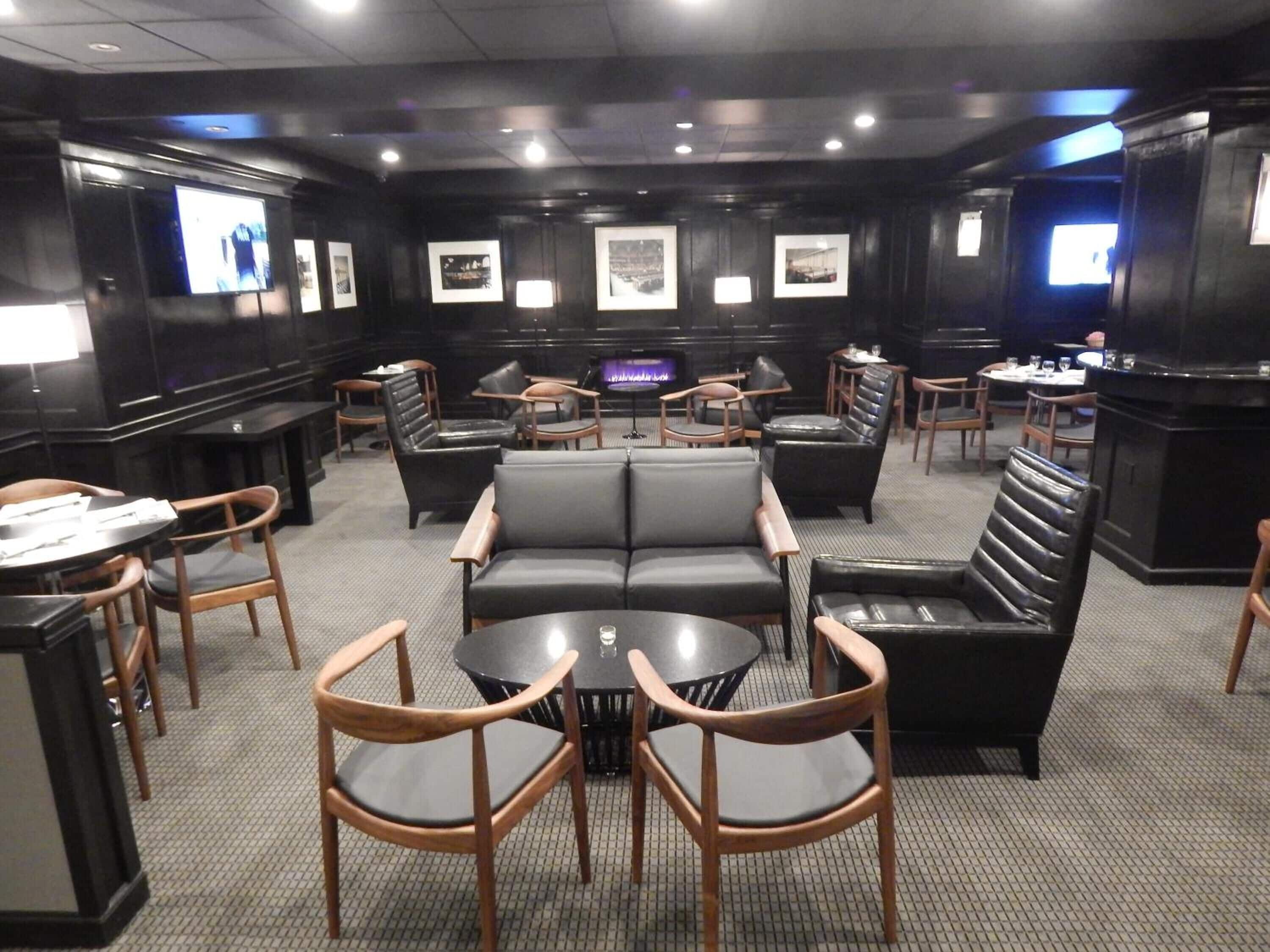 A modern lounge area with leather sofas, wooden chairs, and a central table.