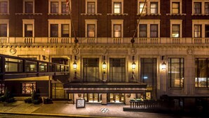 Un hotel con fachada clásica, ventanas amplias y una zona de entrada cubierta con iluminación.