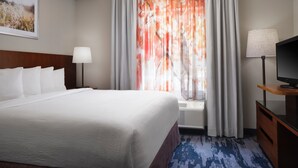 A hotel room with a large bed, a flat-screen TV, a desk with a lamp, and a window with sheer curtains. - Fairfield Inn and Suites by Marriott Austin South (Austin)