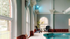 An indoor swimming pool with a view of a brick wall and a window.