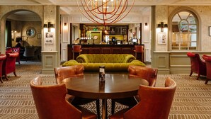 A lobby with a round table, leather chairs, a bar area, and a green sofa.