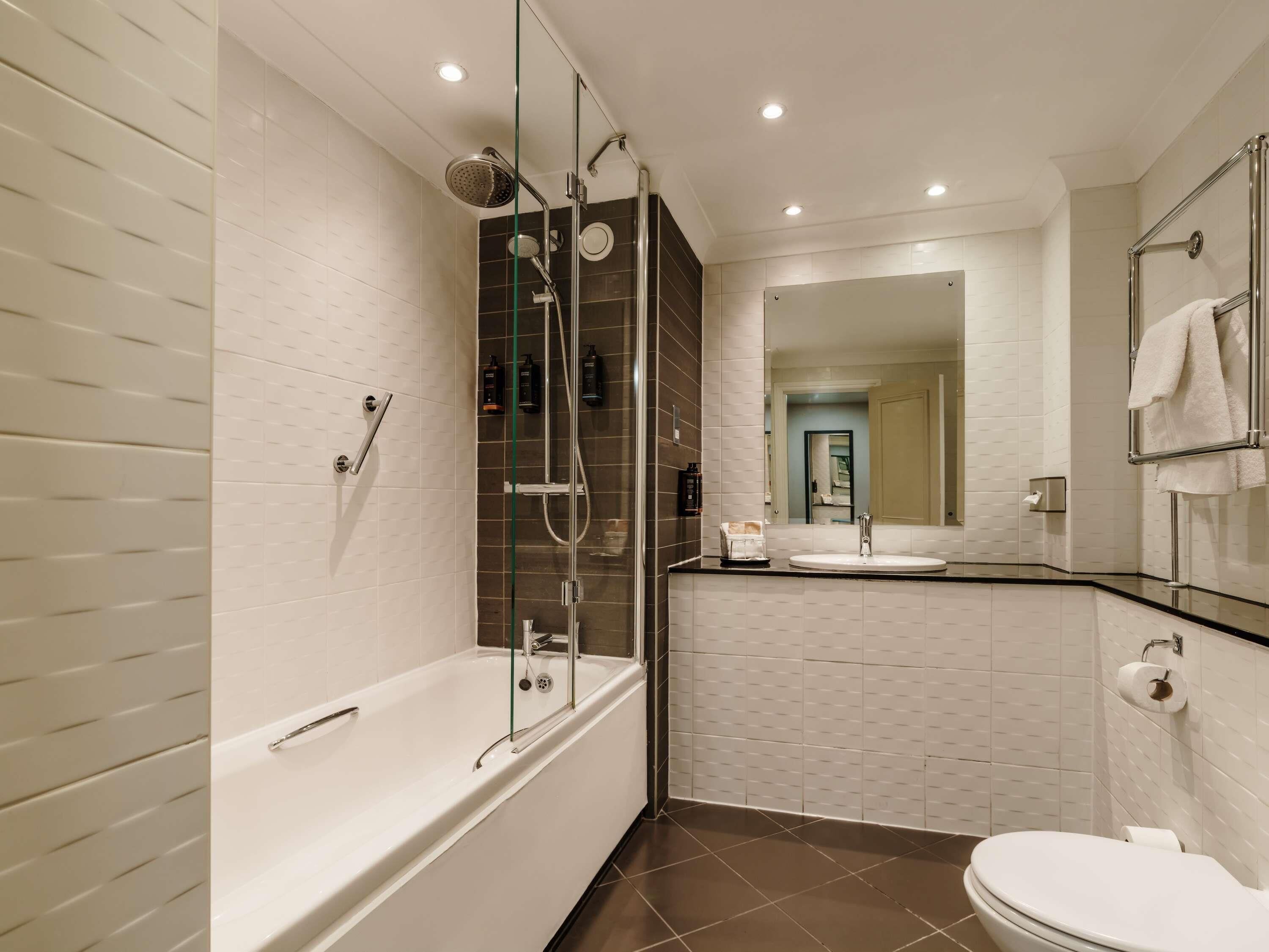 A modern bathroom with a bathtub, shower, and toilet.