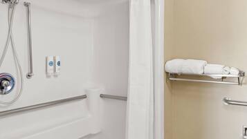 A bathroom with a shower, grab bars, a towel rack, and a toilet.
