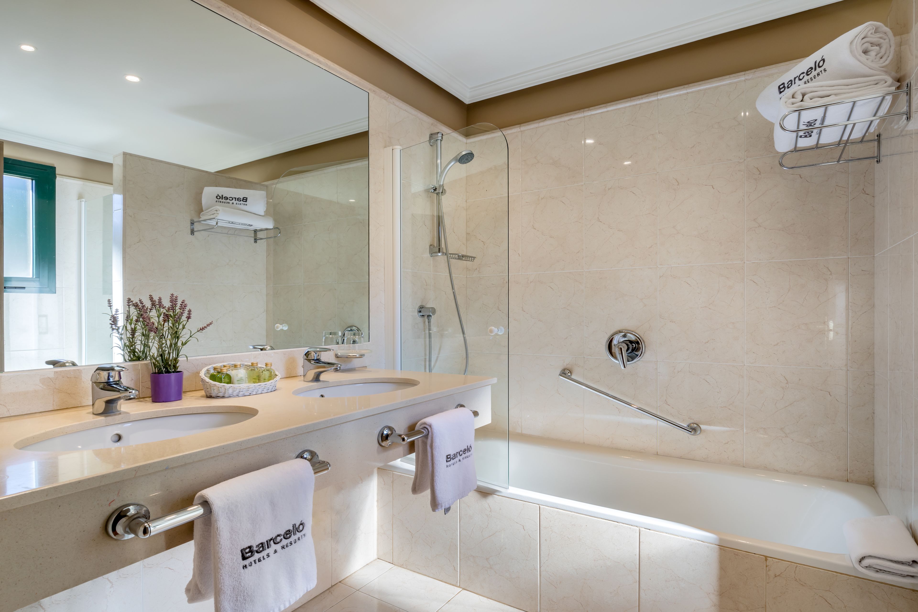 A modern bathroom with dual sinks, a glass-enclosed shower, and a bathtub.