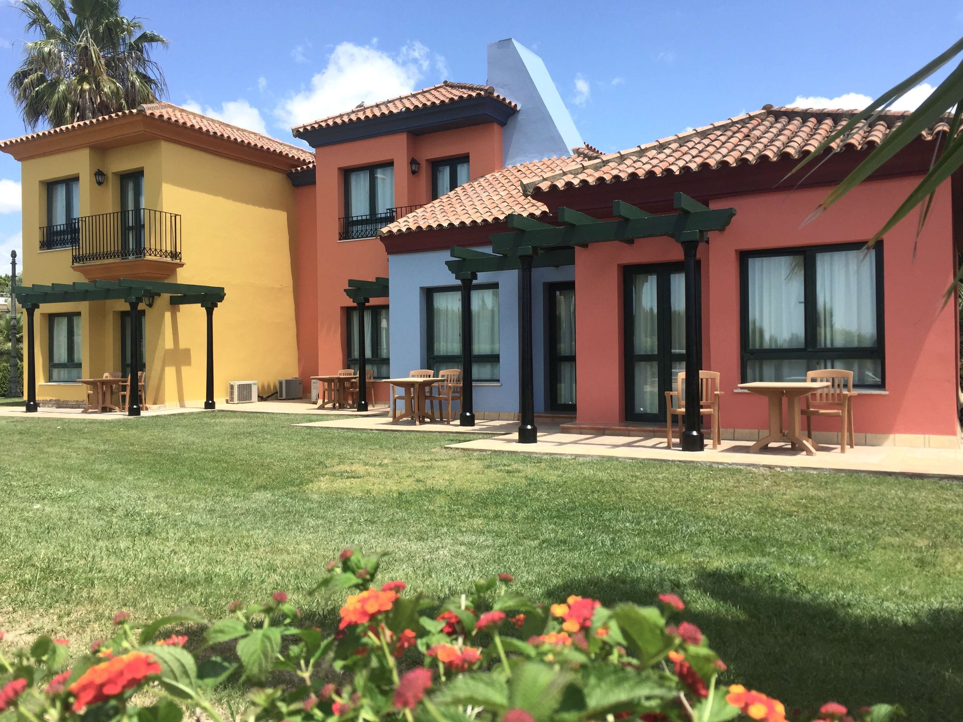 A multi-story building with a patio area featuring outdoor seating and a well-maintained lawn.