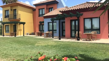 A multi-story building with a patio area featuring outdoor seating and a well-maintained lawn.