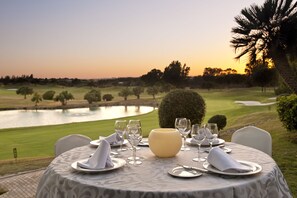 Dine amidst a serene golf course view with a tranquil body of water in the background.